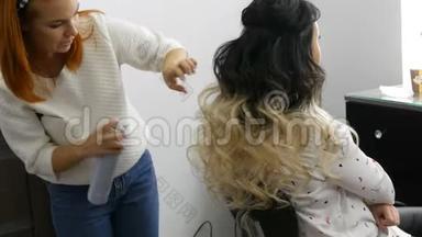 女式美发师在美容院用特制的卷发熨斗做一卷卷发。 长长的美丽